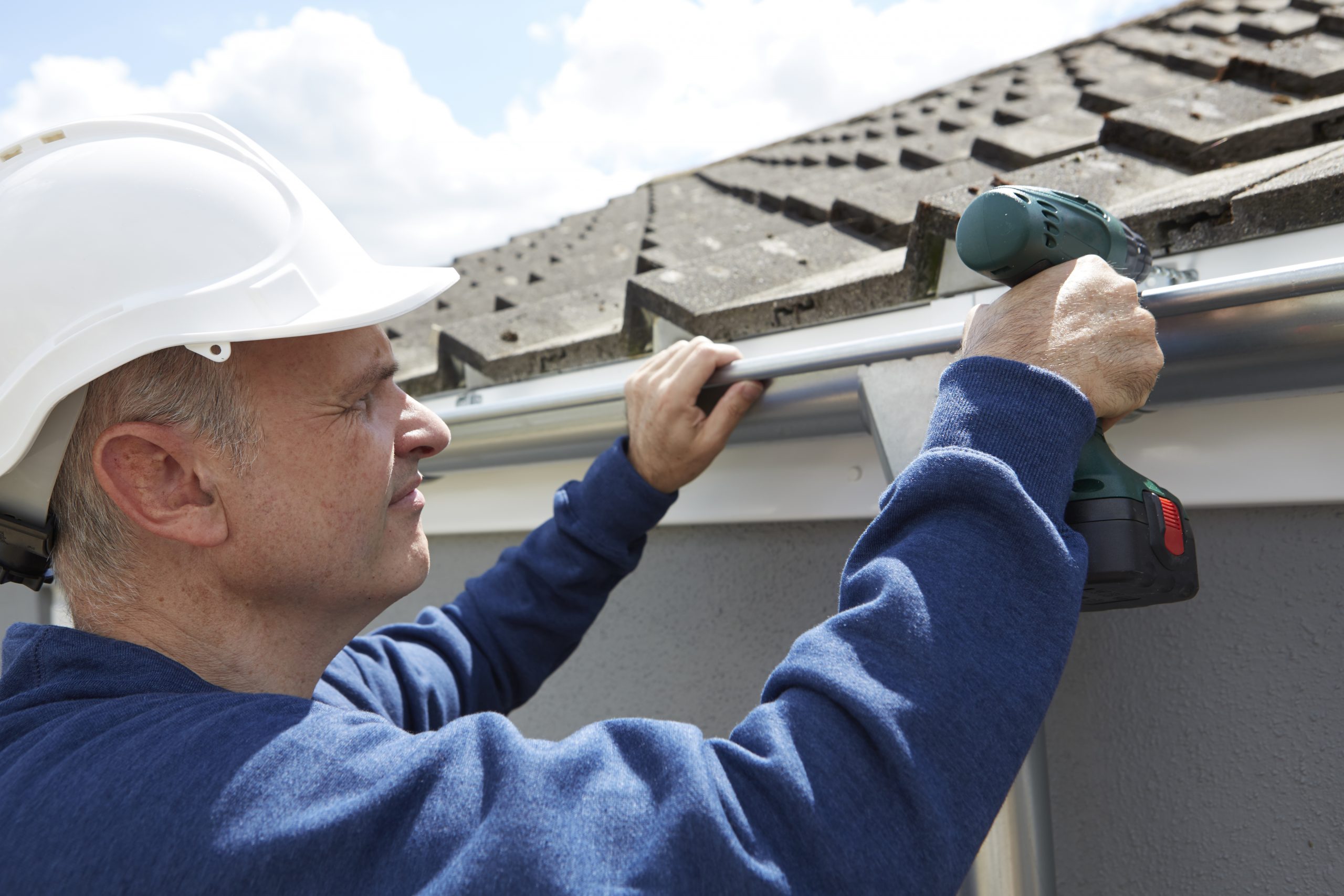 Gutter Contractor Replacing Guttering On Exterior Of House